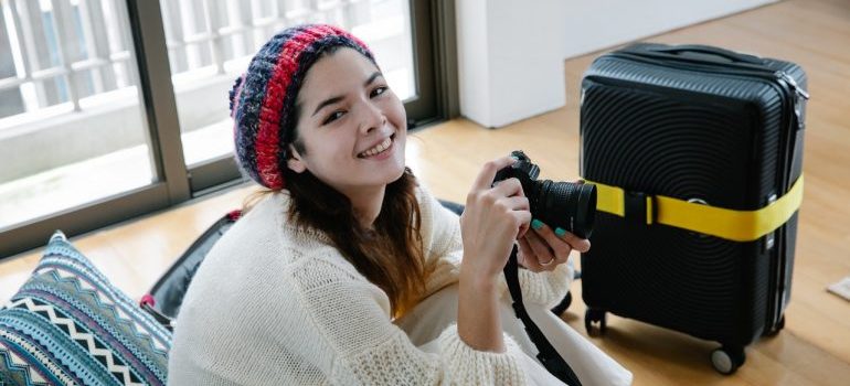 A smiling woman holding a camera, ready for a joyful relocation with local movers Brooklyn.