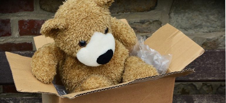 A teddy bear in a cardboard box stuffed with plastic wrap