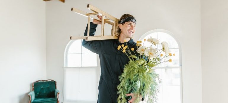 man carrying stool and flowers
