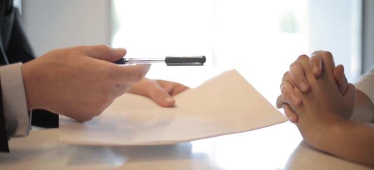 a person holding a document and a pen