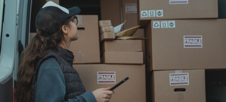 woman holding a pen and looking at cardboard boxes