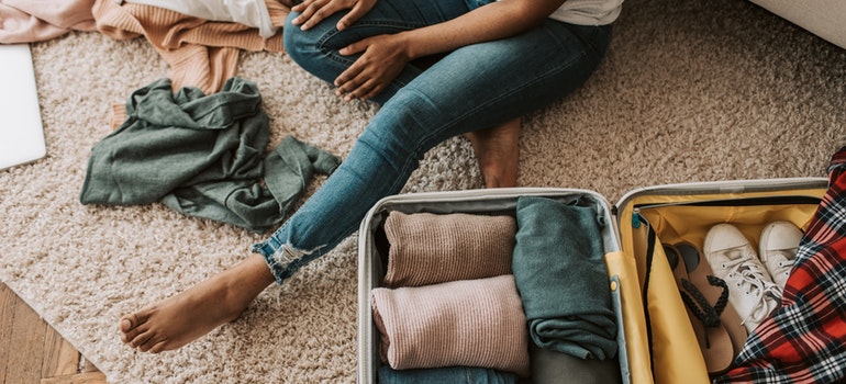 a woman packing clothes in a suitcase