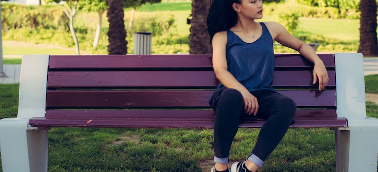 A girl sitting on bench in the park, in of of the best Queens neighborhoods for singles;