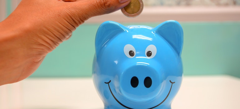 person putting coin into piggy bank representing saving money when buying a vacation home in Hoboken