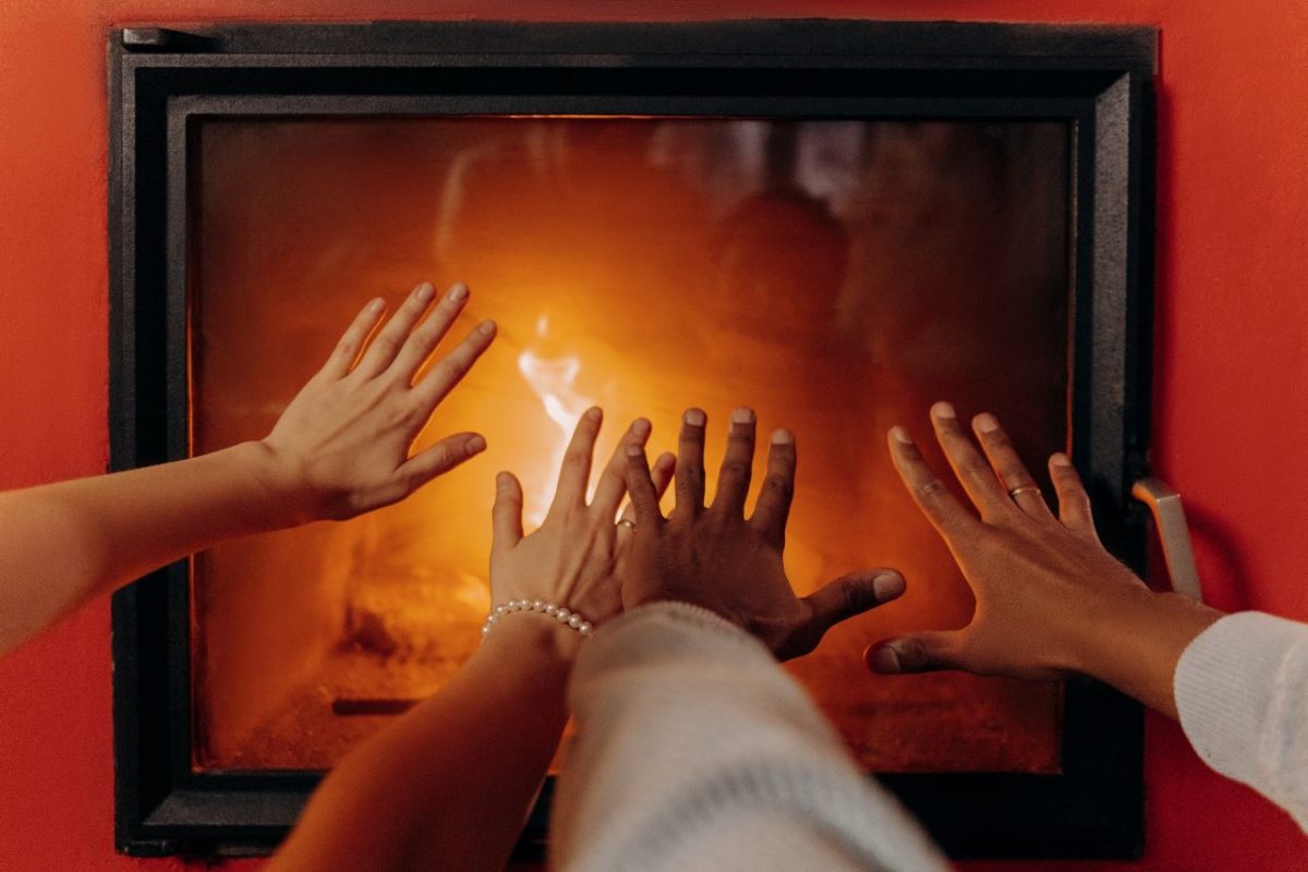 man and woman warming up in front of a fireplace